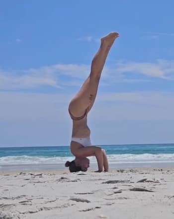 Person doing a headstand on the beach.