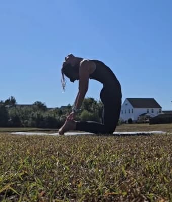 Person doing a camel yoga pose outdoors.